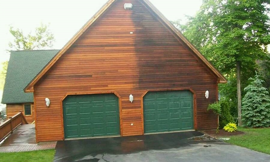 Beautiful wooden house with green garage doors showcasing professional cleaning results
